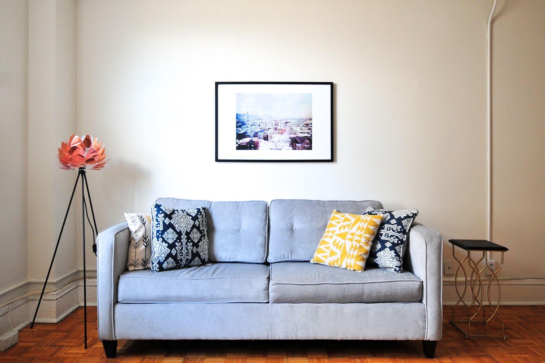 Sala com sofá cinza, quadro e luminária