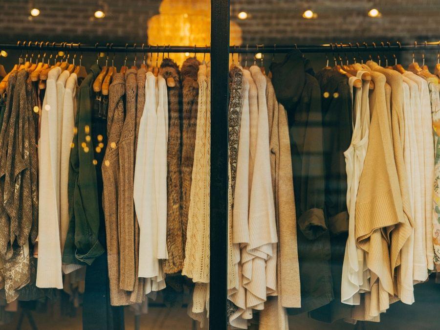 Araras de roupas em tons claros numa loja