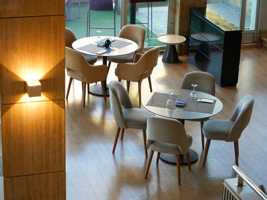 Salão de restaurante com mesas de madeira e cadeiras bege